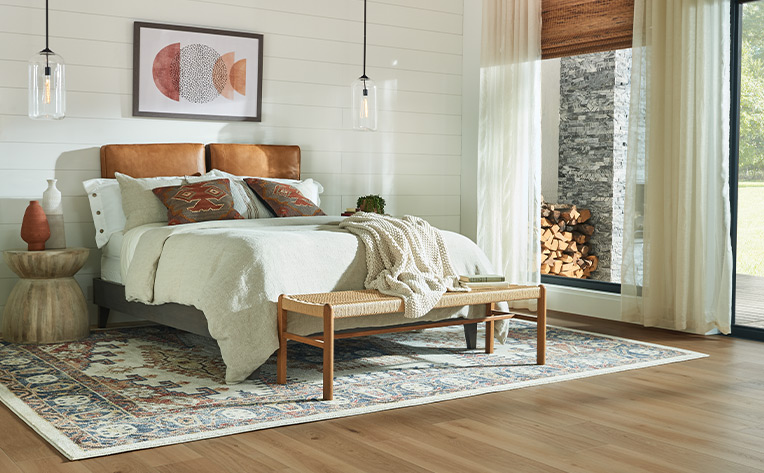 warm toned laminate flooring in bohemian bedroom with area rug