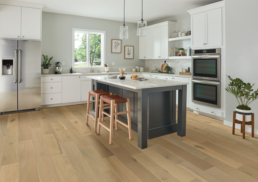 hardwood flooring in kitchen with white cabinets and grey kitchen island with biophilic interior design elements.